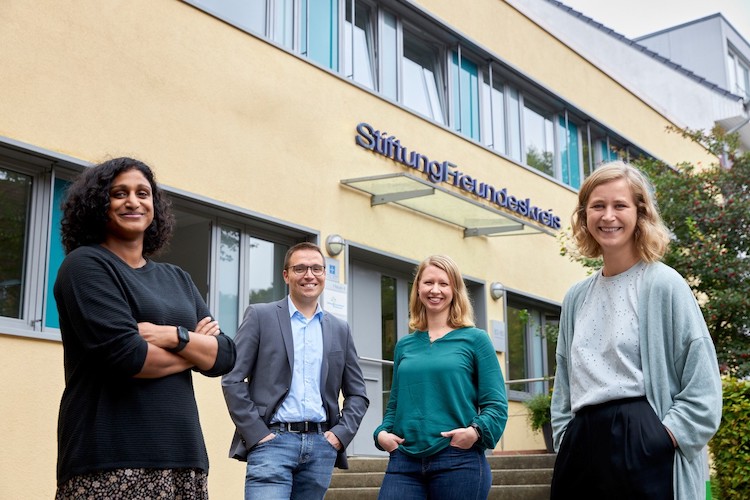 Gruppenfoto vor dem Gebäude der Stiftung Freundeskreis in Hamburg. Drei Mitarbeiterinnen und ein Mitarbeiter, alle lächeln